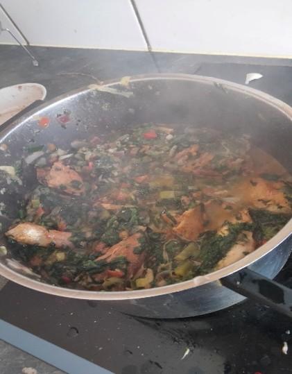 Une casserole sur le feu, de laquelle il dégage de la vapeur, dans laquelle sont en train de cuire les ingrédients de la recette aux épinards sautés.
